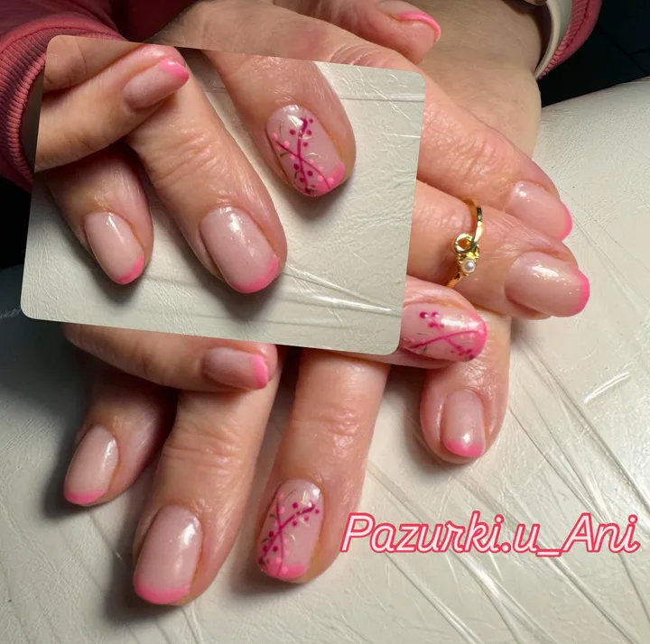 Manicure z różowymi końcówkami i dekoracyjnymi gałązkami na jasnej bazie.